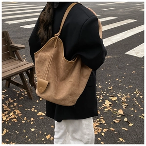 Brown suede tote bag with slim straps styled on a city street background for autumn