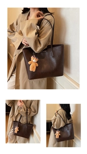 Detail view of large dark brown leather tote bag with stylish plush bear charm accessory