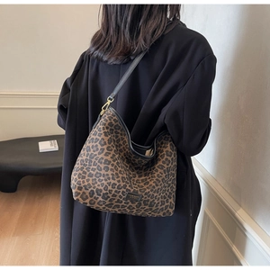 Detail view of leopard print bucket bag with gold hardware and slim black strap