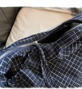 Detail of smooth metal zipper closure on navy blue plaid canvas crossbody bag
