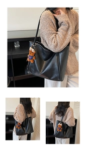 Detail view of black tote bag with smooth leather texture and cute bear pendant accessory
