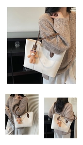 Detail view of cream white tote bag with fine faux leather texture and brown bear charm