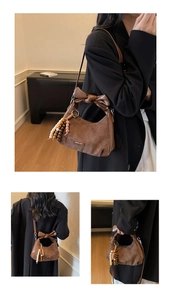Détail d'un sac bandoulière vintage en PU marron mat avec nœud en cuir et charm en perles