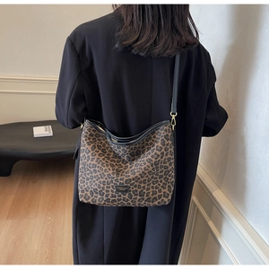 Close-up of leopard print canvas bucket bag with black leather shoulder strap and metal logo
