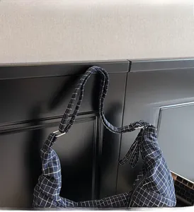 Detail view of navy blue checkered canvas bag showing sturdy strap and metal hardware