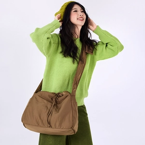 Close-up of brown nylon drawstring crossbody bag styled with casual knitwear