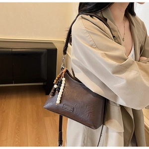 Detail of retro dark brown leather crossbody bag with beaded tassel and fashion metal tag