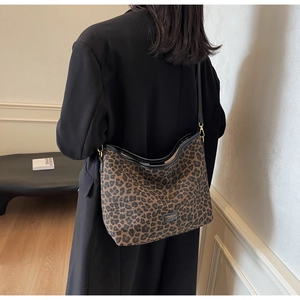 Detail view of large leopard print bucket bag with black leather trim and metal logo