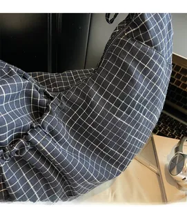 Detailed view of the soft plaid fabric texture on a navy blue casual shoulder bag