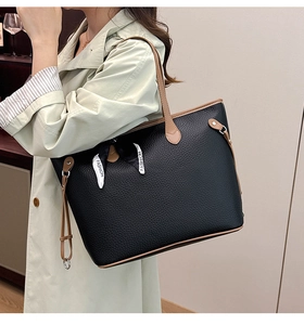 Detail of black pebbled leather tote bag with brown handles and fashion ribbon