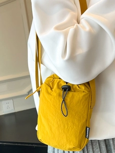Minimalist bright yellow nylon drawstring crossbody bag with fashion label and shoulder strap