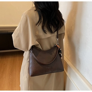 Detail view of vintage brown hobo bag featuring grain leather texture and beaded charm