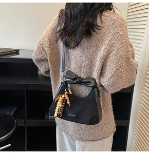 Détail du sac à bandoulière carré avec nœud en cuir 3D et breloque en perles de bois
