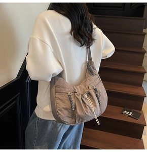 Detail of dark taupe nylon crossbody bag with zipper pockets and utility style
