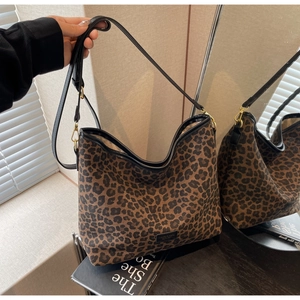 Detail of leopard print bucket bag with black trim and gold hooks shown in mirror reflection
