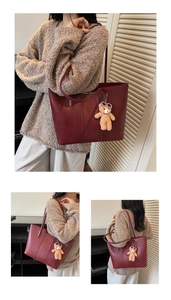 Detail of burgundy PU leather tote bag with vertical stitching and bear plush charm