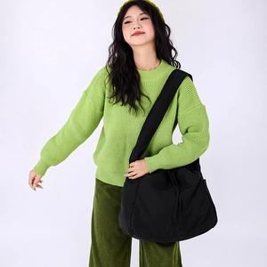 Detailed view of black nylon drawstring crossbody bag with wide shoulder strap on model