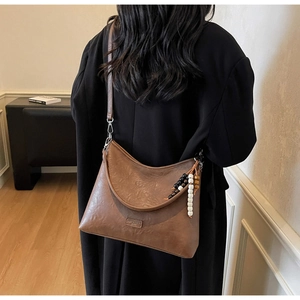 Brown semi-circle shoulder bag with beaded fringe charm shown on a model's back