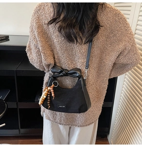 Détail du sac sous l'aisselle noir avec poignée à nœud en cuir et pendentif en bois
