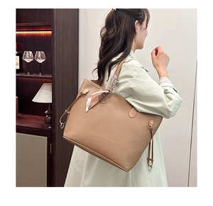 Close-up of brown pebbled leather tote bag with stylish silk scarf detail and metal buckles