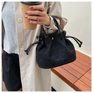 Detail of a matte black drawstring bucket bag featuring sleek metal ring hardware accents