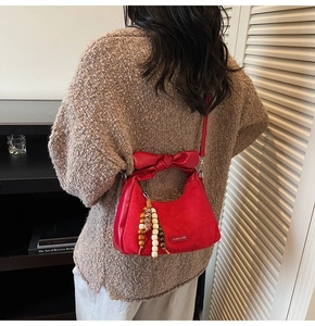 Détail du sac rouge en daim avec une poignée nœud en cuir et un charm en perles