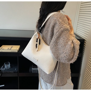 Detail of cream white bucket bag with colorful beaded tassel pendant and shoulder strap