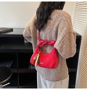 Détail du sac à bandoulière mat rouge avec grand nœud et gland en perles de bois