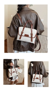 Detail of cream messenger bag with brown trim, lychee texture, and dual buckle straps