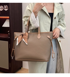 Close-up of brown pebbled leather tote bag with stylish printed fashion silk scarf on handle