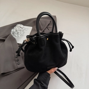 Detailed close-up of a black suede drawstring bucket bag with elegant gold hardware accents