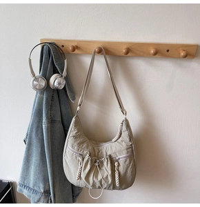 Detail of grey-green nylon crescent bag featuring functional pockets and woven zip pulls