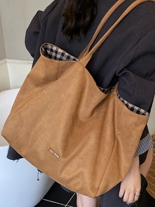 Brown suede tote bag with checkered lining and minimalist leather patch on a model