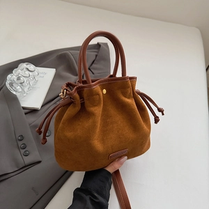 Detail view of brown suede bucket bag featuring drawstring closure and fashion logo tag