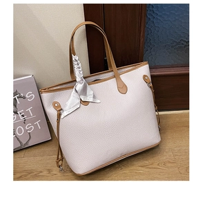Detailed macro view of cream-colored lychee leather tote bag with brown handles and silk scarf