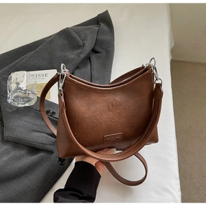Detail of vintage brown crescent bag showing leather texture and silver buckle