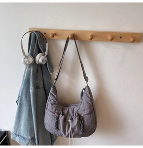 Detail of purple-grey crescent hobo bag with drawstring and multi-pocket design