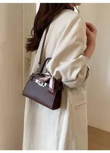 Detail of dark brown litchi pattern leather bag with silver buckle and silk scarf
