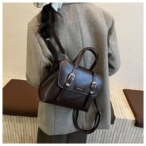 Detail view of dark brown vintage faux leather backpack with dual gold buckle closure