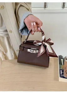 Detail of a brown lychee pattern leather handbag with a patterned silk scarf on handle
