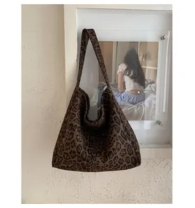 Dettaglio della borsa tote leopardata in tela con ampia tracolla appesa alla parete