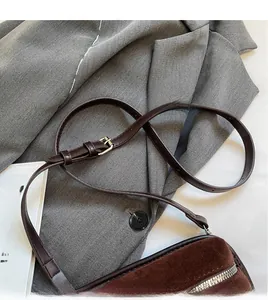 Detail of vintage brown suede crossbody bag showing adjustable strap and silver zipper