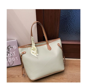Detail of light green tote bag with brown leather straps and decorative yellow silk scarf