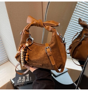 Détail du sac en cuir marron vintage avec poignée en nœud et pompon de perles élégant