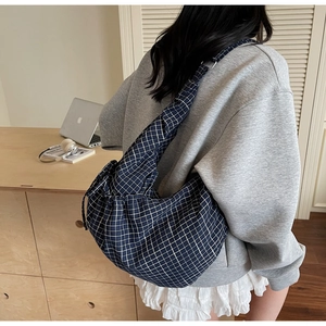 Detail of navy blue checkered crossbody bag with drawstring closure and wide strap