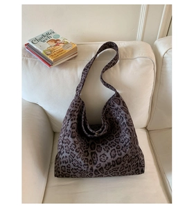 Vista dettagliata della borsa hobo leopardata in tela su un divano in tessuto bianco