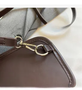 Detailed close-up of silver hardware and stitching on a dark brown suede crossbody bag