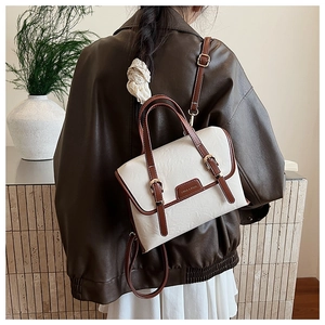 Detail of cream and brown vintage backpack featuring pleated texture and metal buckle strap