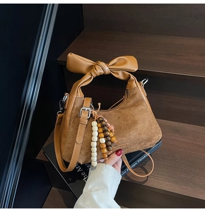 Détail du sac en daim marron avec poignée en nœud de cuir et charmes en perles de bois