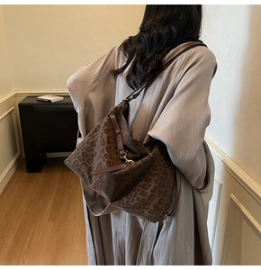 Detailed view of the leopard print suede tote bag with brown leather strap and gold buckle